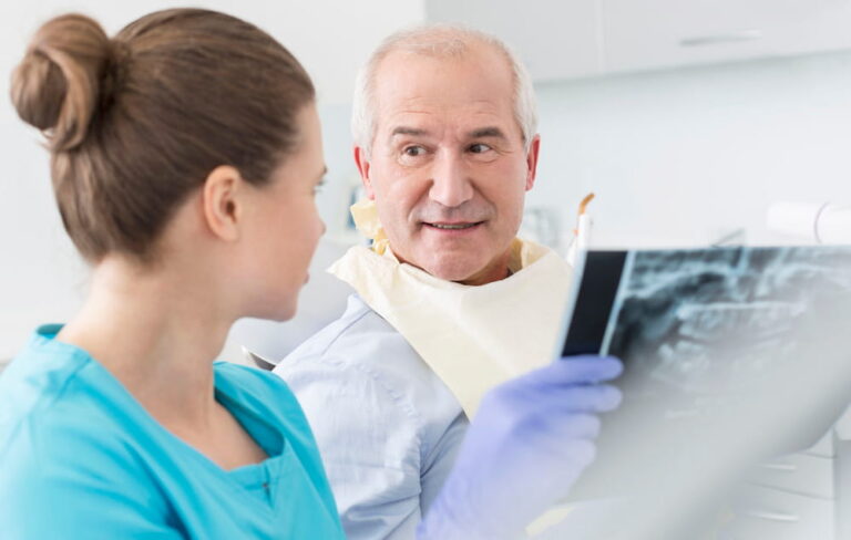 Dentist and senior patient discussing over x-ray at clinic