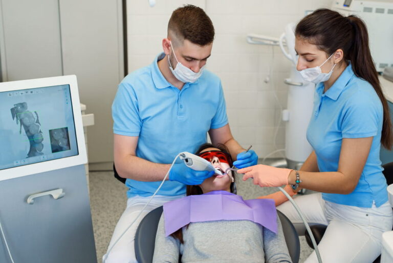 Professional male dentist with his female assistant doing a digital model of patient's teeth with modern 3D scanner. Modern equipment in medicine.