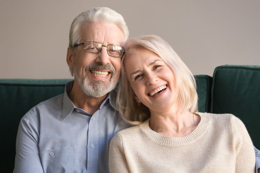 Head Shot Laughing Retirees Pretty Couple Sitting On Couch At
