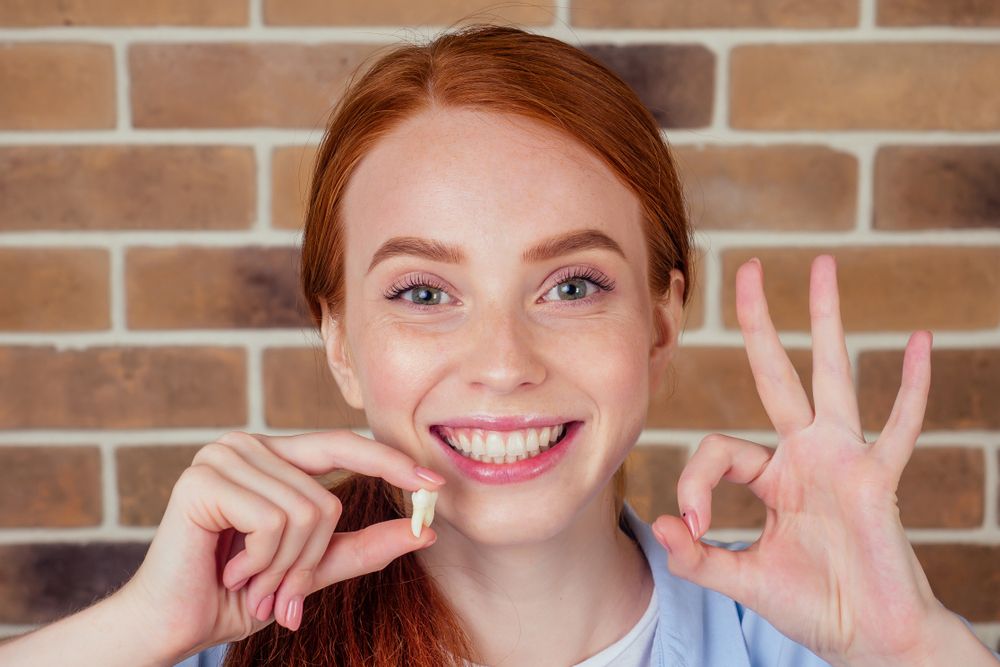 Redhaired Ginger Female With Snow-white Smile Holding White Wisdom Tooth