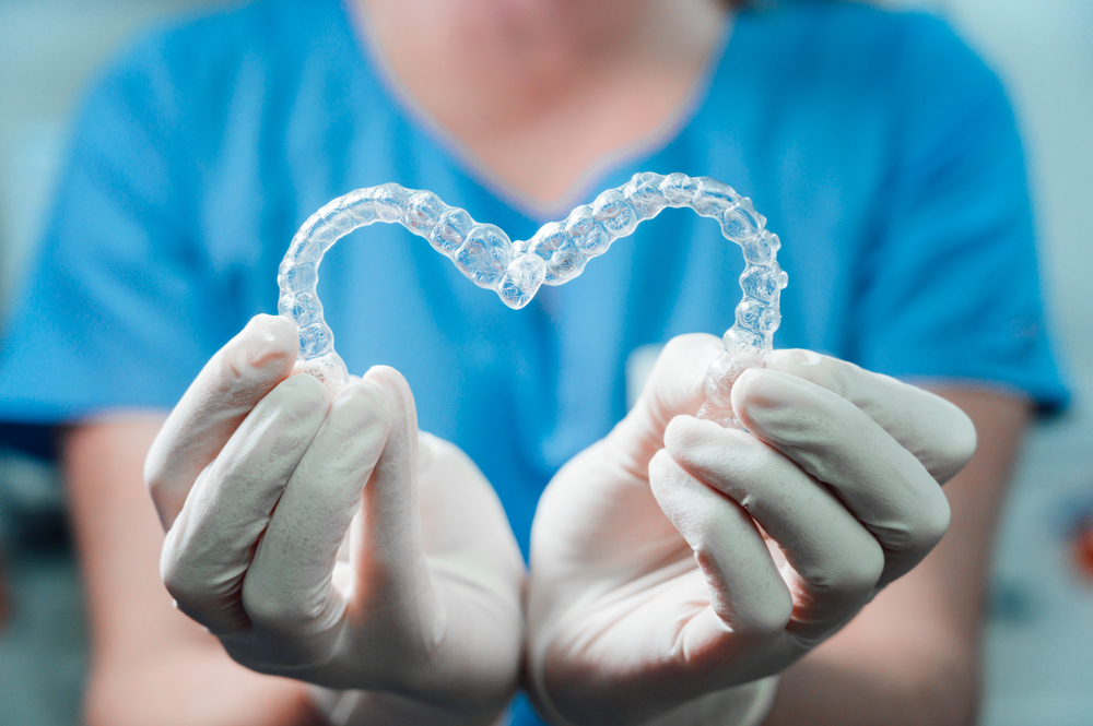 Female Doctor Holding Two Transparent Heart-shaped Dental Aligners