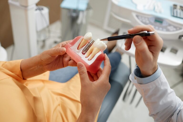 Close-up of unrecognizable senior woman holding tooth model during consultation on dental implant surgery in dental clinic