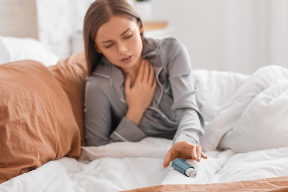 Sick young woman with inhaler in bed
