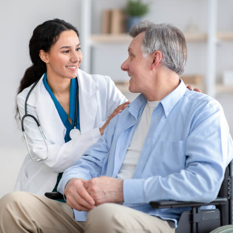 Impaired senior man in wheelchair and young nurse taking care of him at home