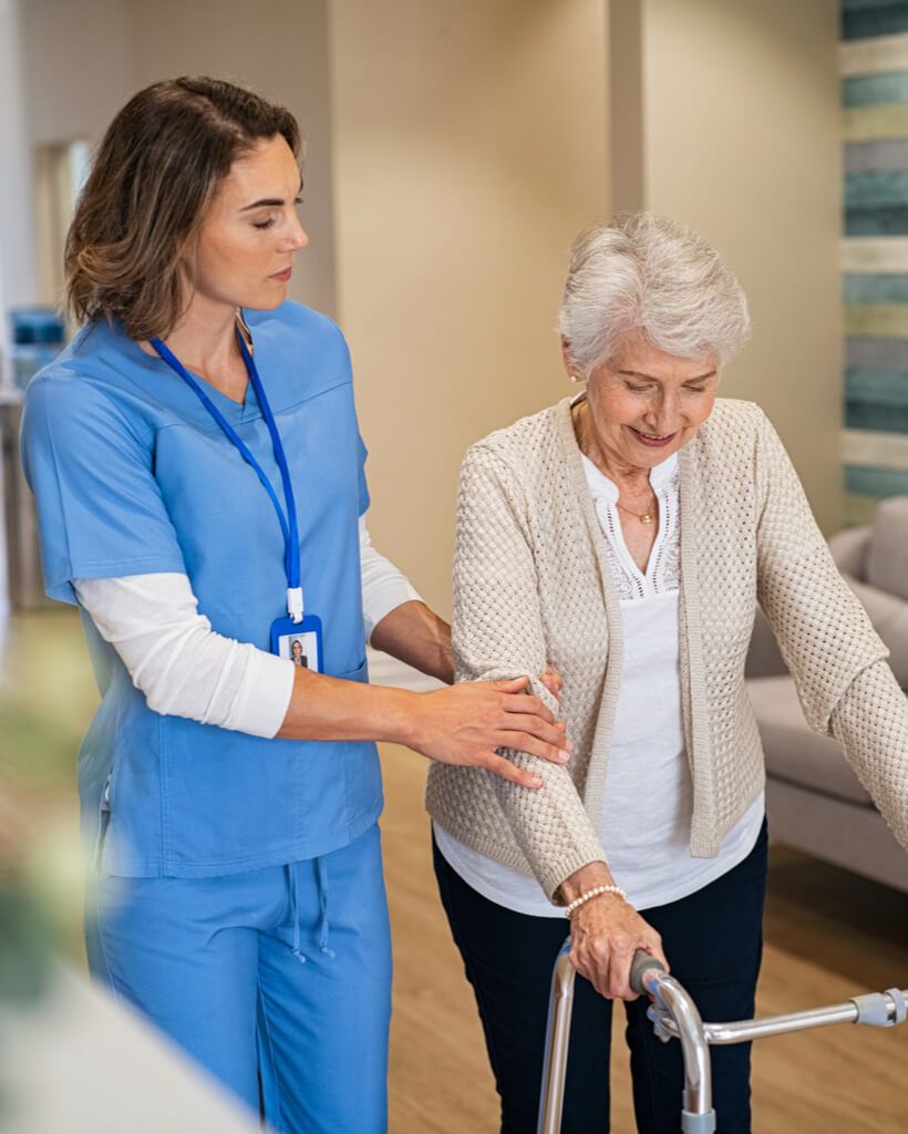 Lovely nurse helping old woman to walk at nursing home with walker