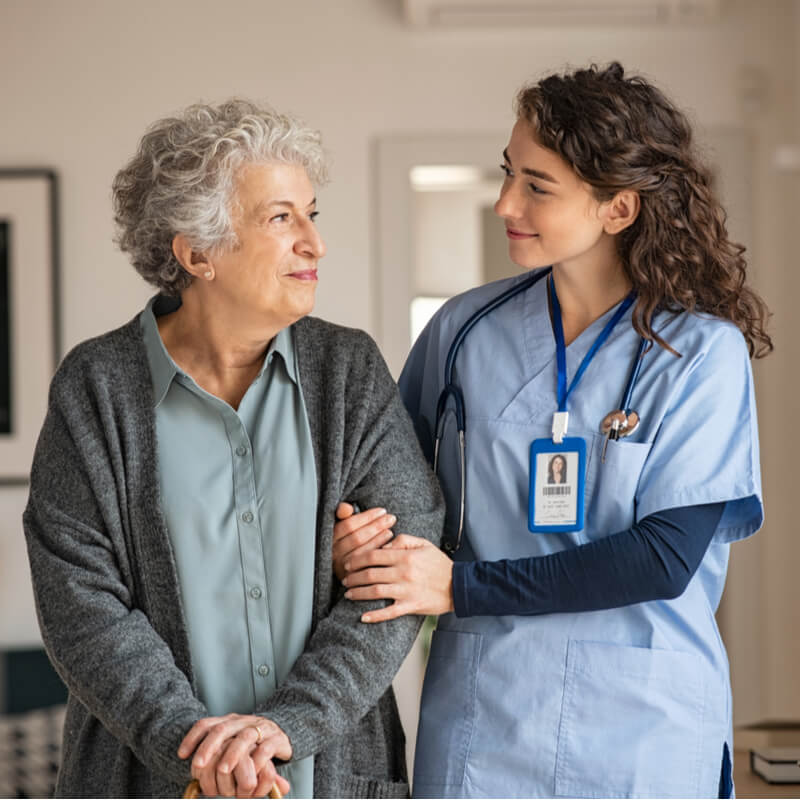 Young caregiver helping senior woman walking