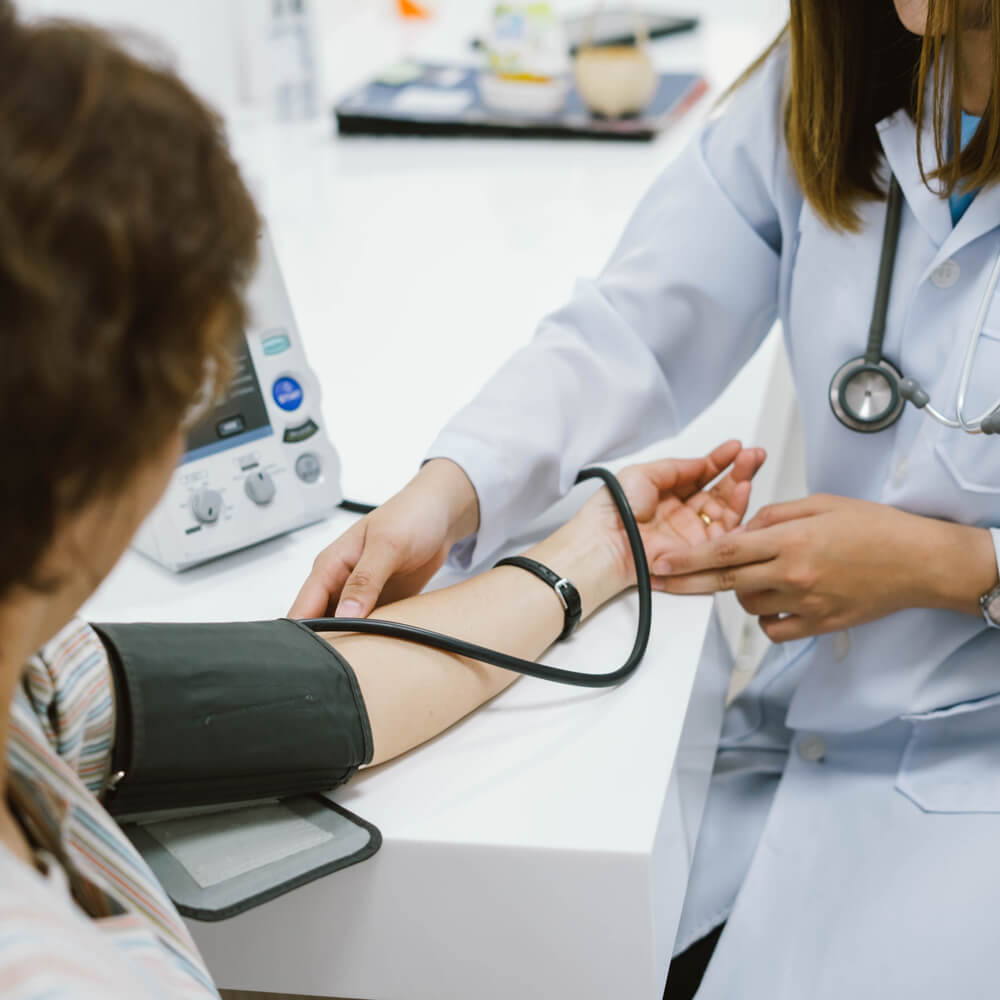 young female doctor checking senior patient blood pressure.