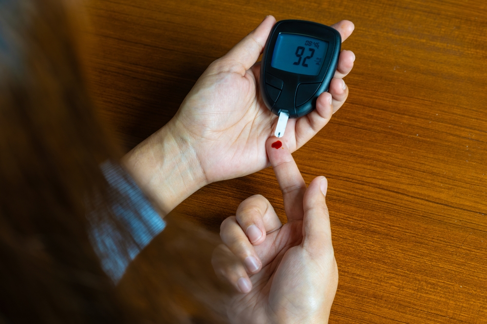 Woman's hands checking diabetes and hyperglycemia with digital blood sugar meter.