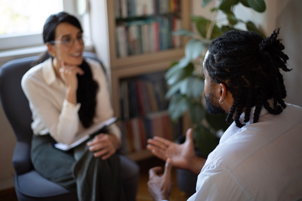 Image showing black male client talking about his mental health with his psychotherapist who carefully listens to him 