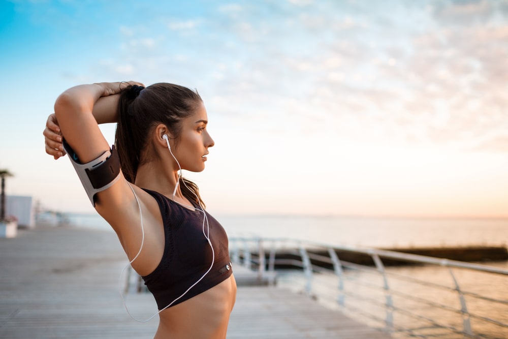 Young beautiful sportive girl training at sunrise over seaside.