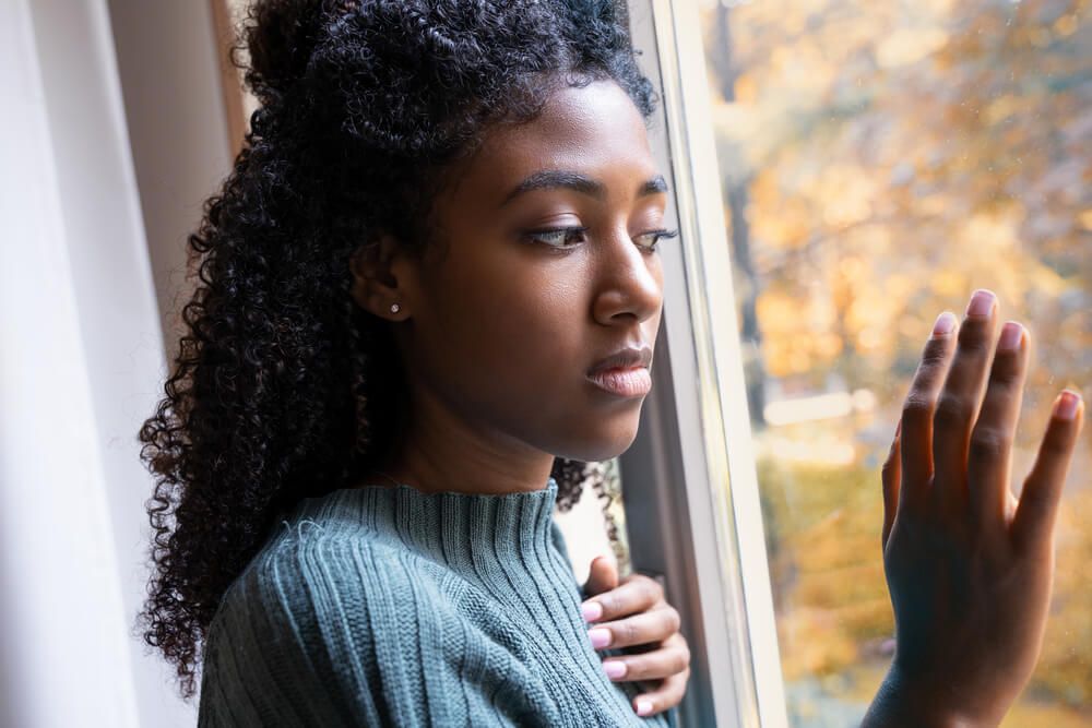 female stares outside her window