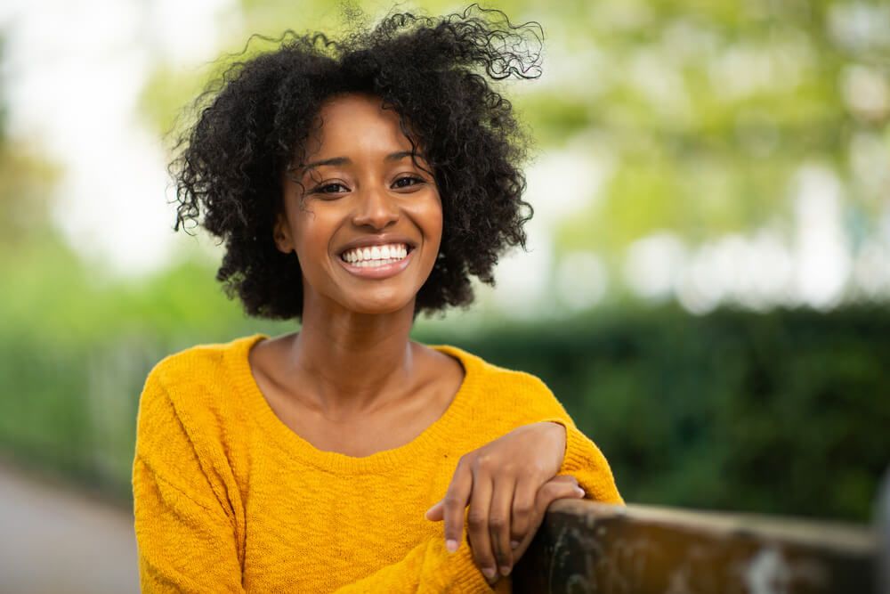 Beautiful young woman sitting on bench and smiling