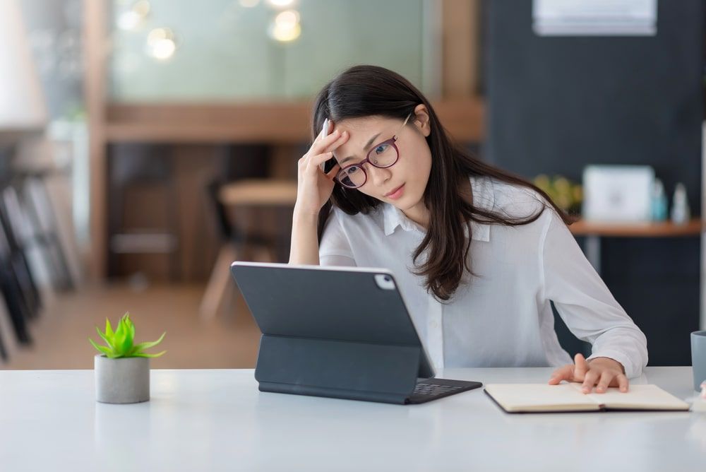 woman tired and overthinking from working with a tablet